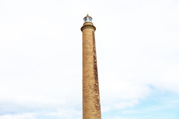 Lighthouse against cloudy sky. Tall tower with a light on top