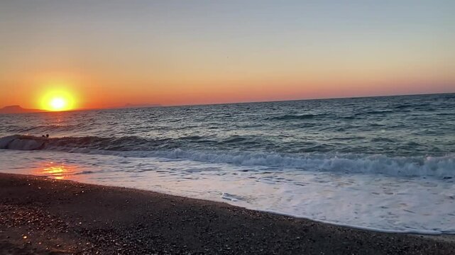 Slow motion at sunset, crashing noisily on a sandy beach and foaming waves, on the island of Crete in Greece in 2023