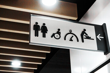 A white and black sign for the toilet and prayer room is on the wall.