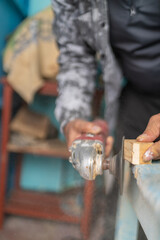 Woodcarver sanding wood with electric sander in workshop