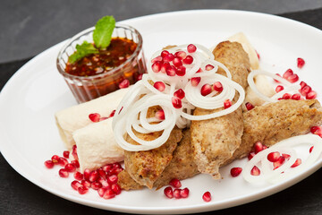 Traditional grilled kebab with pomegranate, onions, spicy sauce for flavorful culinary experience