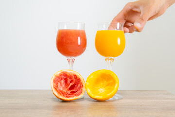 Obraz premium Two glasses of blood and regular orange juice and orange slices on a table. difference and kinds of oranges color and flavor.