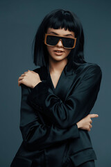 Beautiful asian woman in sunglasses and black suit, closeup studio shot on gray background with black and white effect, strong lighting emphasizing elegance and style