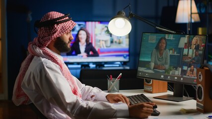 Arabic employee holding online video conference meeting with remotely working coworkers. Teleworking executive sitting at desk in stylish apartment, discussing with colleagues during video call