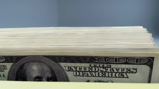 Bundle of 100 dollar bills is recalculated on counter. Phrase The unted states of america is in the center frame. Concept tax and mortgage