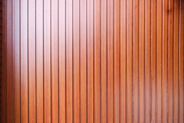 Fototapeta premium A close-up image of a wooden wall, showcasing its natural texture and warm brown tone. The vertical planks create a repeating unique pattern.