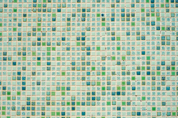 Residential building wall with small mosaics looking like green and brown pixels.