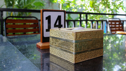 A close-up shot of a table setting with a tissue box and a sign that reads '14'. The table is set...