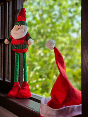 Boneco de Papai Noel e gorro vemelho sobre Janela com Vista para a Natureza