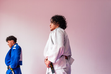 Exhausted judo fighters in dojo with pink wall at background with copy space