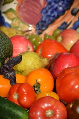 Tomatoes, cucumbers, apples, grapes and pears near a ceramic plate with a fruit pattern