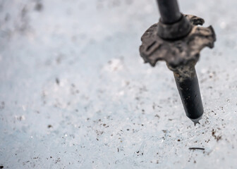 Selective focus on the point of a spiked hiking pole being used for traction support on ice. 
