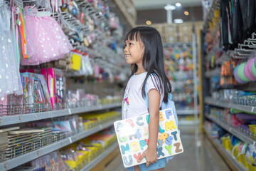 A young girl is shopping in a store with a backpack