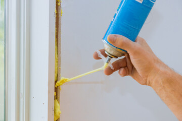 Construction foam is blown into gap between window wall by worker