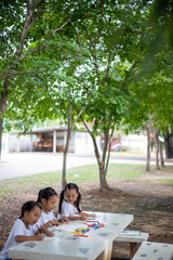 Three young girls are sitting at a table with markers and coloring books.