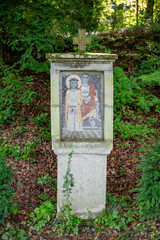 A small mosaic of religious figures displayed at Klosterruine Heisterbach, surrounded by greenery and showcasing detailed craftsmanship.