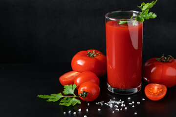 Delicious tomato juice on a black background. Vegetable drink for vegan and healthy eating.