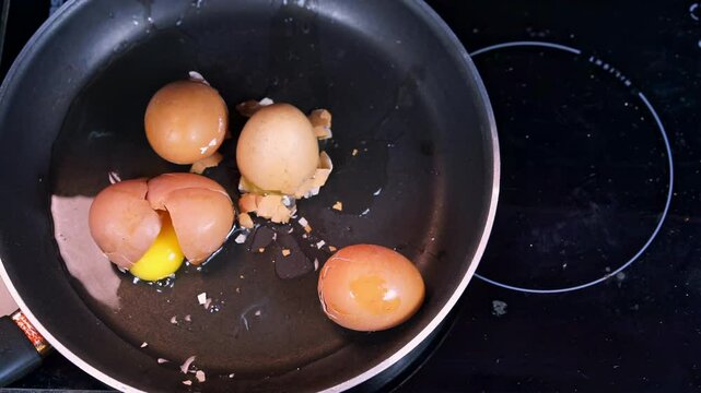 Raw chicken egg in shell fall on frying pan on induction cooker Sleepy bad cook clumsily prepares breakfast omelette Advertising of cooking courses, healthy food recipe Too lazy to cook, food delivery