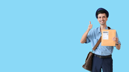 Handsome young postman with letter showing thumb-up on color background