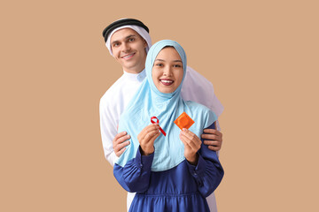 Beautiful Muslim couple with red ribbon and condom on brown background. AID awareness concept
