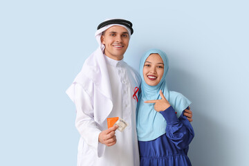 Beautiful Muslim couple with red ribbons and condoms on blue background. AID awareness concept