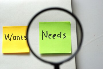 The concept of wants vs needs with magnifying glass, financial priority concept