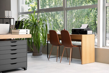 Modern printer on table near window in office