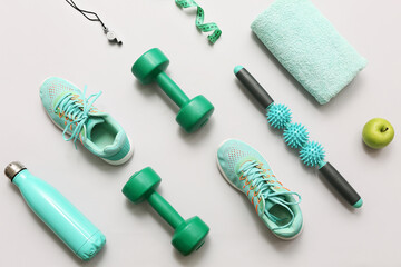Sneakers, apple, measuring tape and different sports equipment on grey background