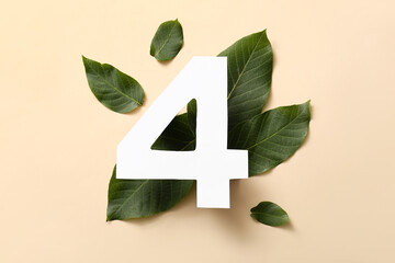 Green leaves with paper number four on beige background. Top view