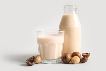 Glass and bottle of fresh macadamia milk on grey background
