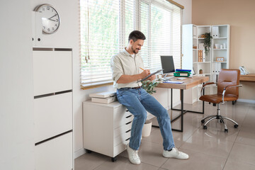 Male accountant writing on clipboard in office