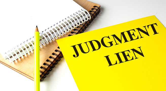 JUDGMENT LIEN text on yellow paper with notebooks
