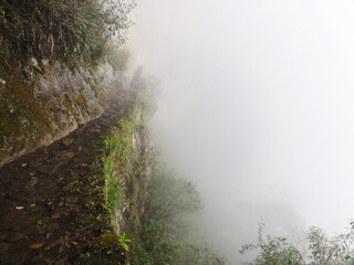 Stone path clinging to the side of a mountain disappears into thick fog
