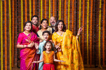 Indian family with grandparents and kids, excited and pointing in traditional Diwali attire