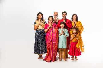 Indian family in festive mood, welcoming guests with Namaste while looking at the camera
