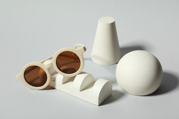 Decorative podiums with stylish sunglasses on grey background