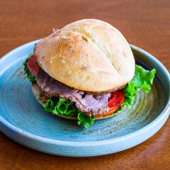 Fresh and tasty roast beef sandwich on a plate, featuring fresh lettuce and tomato