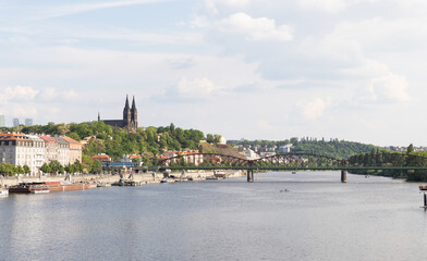Fototapeta premium View from the embankment of Vltava river to the Railway Bridge and Saints Peter and Paul Basilica in Vysehrad in Prague in Czech Republic