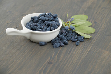 White bowl filled with Honeyberry haskap berries on wooden table
