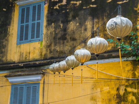 Vietnam, Hoi An. Old town historic district (UNESCO World Heritage Site). Electric lanterns hanging near an old yellow building.