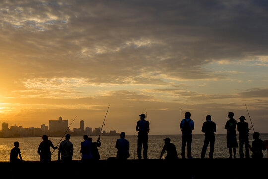 Cuba, Havana, fishermen on Malecon at sunset (silhouette).