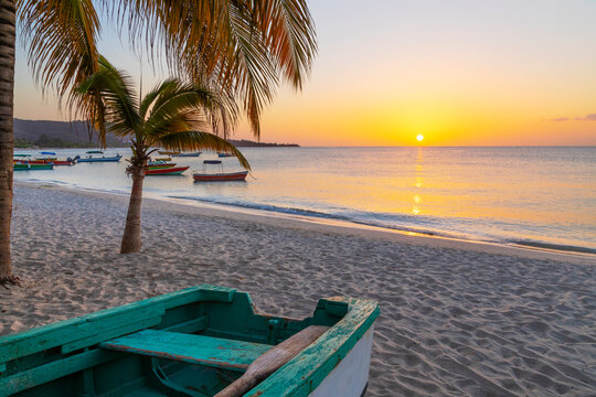 Caribbean, Grenada, Grenadines. Sunset and wooden fishing boat on Grand Anse Beach.