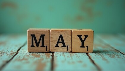 Image of wooden cubes spelling 'MAY' on a rustic green background, ideal for May Day or Labor Day promotions, with copy space.