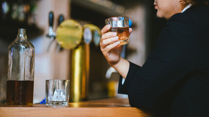 A young businessman holds a glass of whiskey, toasting with friends at an upscale bar. The scene captures the essence of luxury and celebration, with a focus on camaraderie and the nightlife atmospher