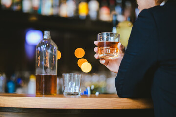 A young businessman holds a glass of whiskey, toasting with friends at an upscale bar. The scene captures the essence of luxury and celebration, with a focus on camaraderie and the nightlife atmospher