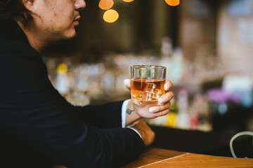 A young businessman holds a glass of whiskey, toasting with friends at an upscale bar. The scene captures the essence of luxury and celebration, with a focus on camaraderie and the nightlife atmospher