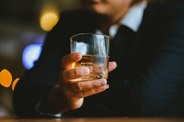A young businessman holds a glass of whiskey, toasting with friends at an upscale bar. The scene captures the essence of luxury and celebration, with a focus on camaraderie and the nightlife atmospher