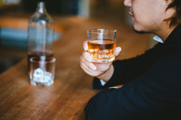 A young businessman holds a glass of whiskey, toasting with friends at an upscale bar. The scene captures the essence of luxury and celebration, with a focus on camaraderie and the nightlife atmospher