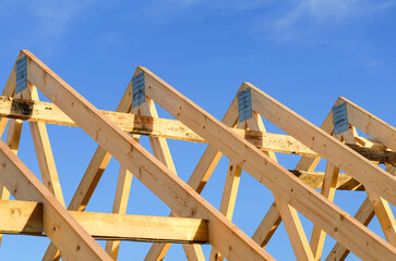 Wooden Roof Trusses Under Clear Blue Sky at Construction Site in Afternoon