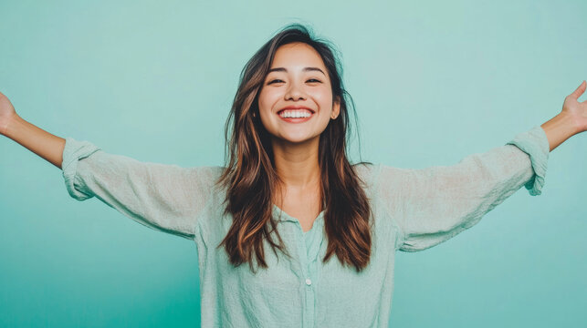 Young Asian woman with open arms isolated on blue background , studio shot of a beautiful Asian American girl with happy smiling face welcome with open arms on teal color backdrop
